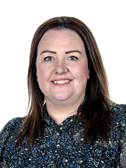 A woman with straight brown hair and a floral blouse, smiling