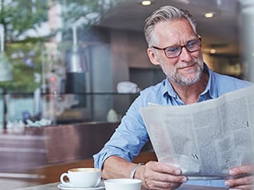 Man reading newspaper in coffee shop