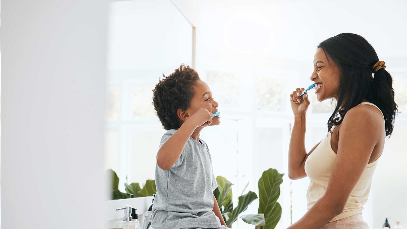 Mother brushing teeth with son in bathroom