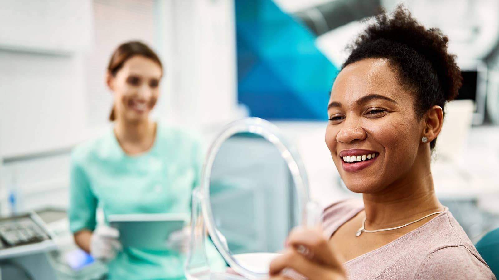 Smiling lady holding mirror in dentists chair