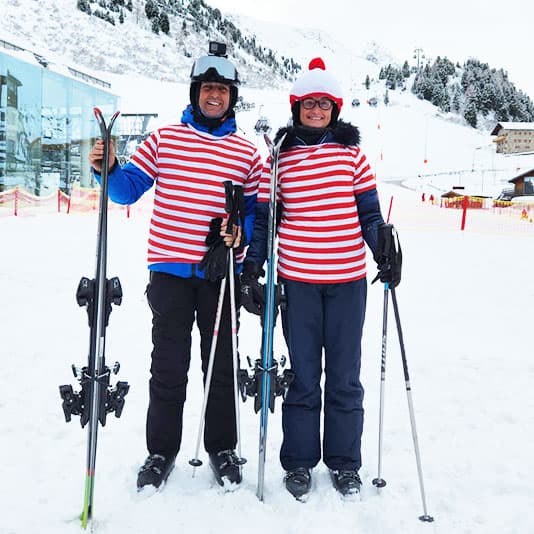 Two people dressed in Where's Wally fancy dress stood on a ski slope