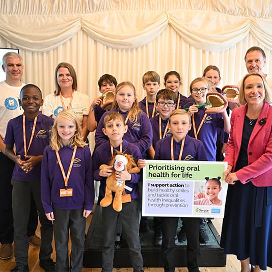 Group of children holding dental models and a sign about oral health