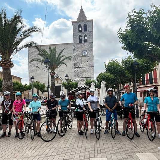 Denplan dentists posing with their bikes in a market square with a church
