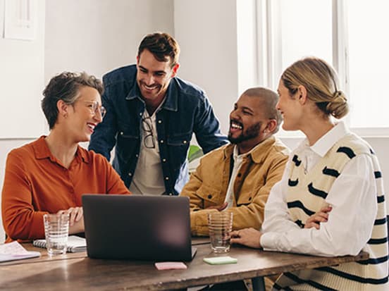 Colleagues gathered around a laptop and smling
